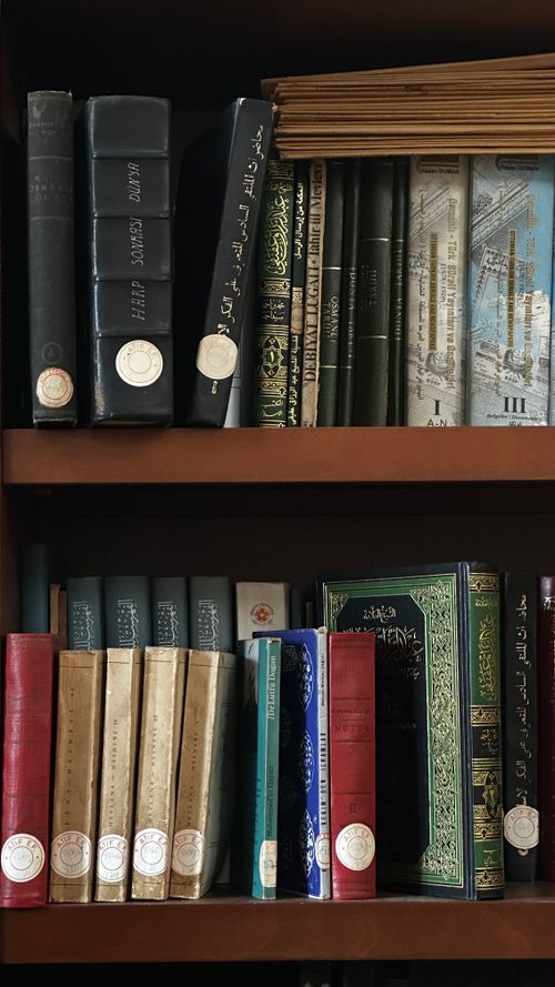 Free Collection of antique books with decorative spines on a wooden bookshelf in a library. Stock Photo