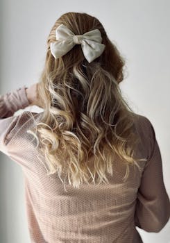 Back view of woman with stylish curly blonde hair and elegant bow.
