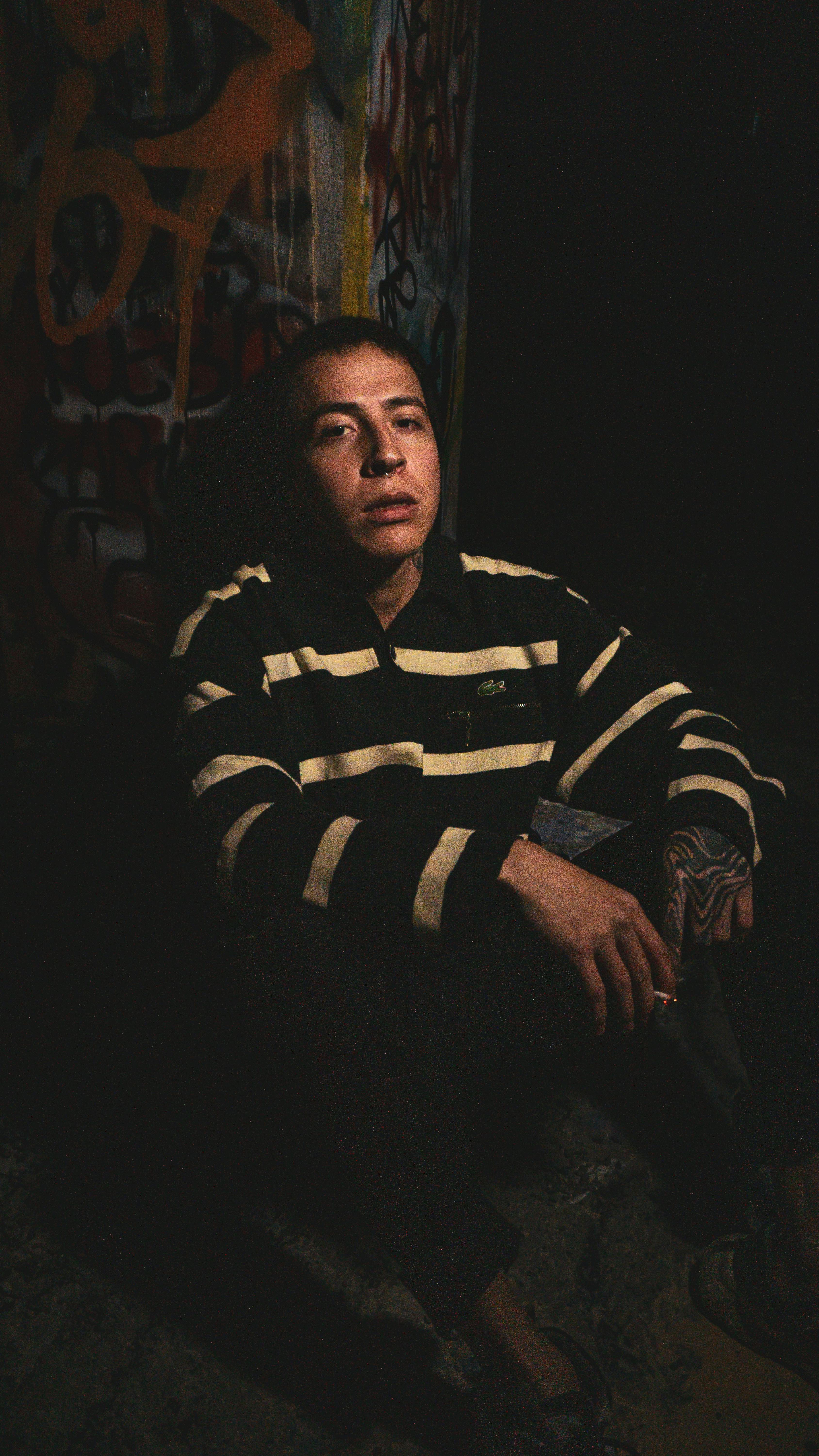 Dramatic portrait of a young man in striped sweater against colorful graffiti background.