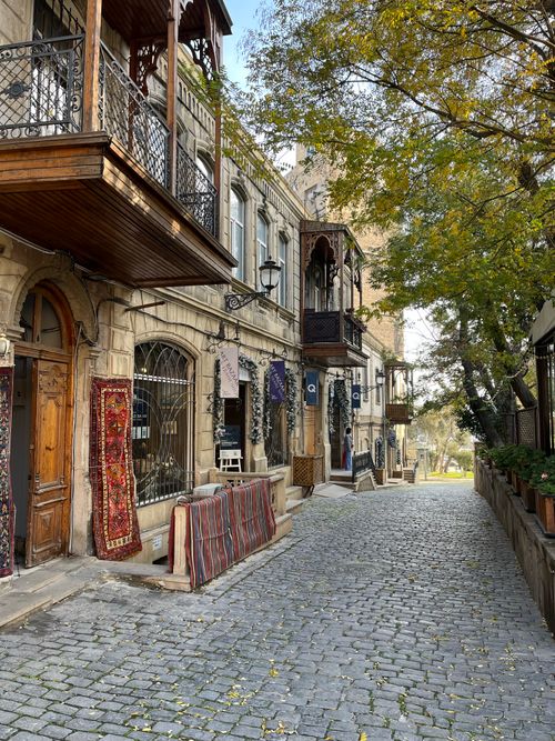 Free Cobbled street with traditional buildings and colorful rugs on display. Stock Photo