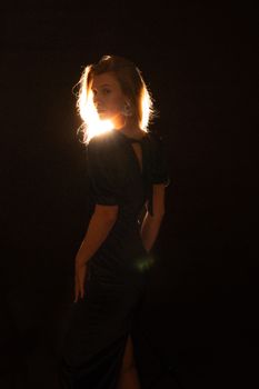 A stylish woman in a black dress captured in dramatic backlighting for a vintage effect.