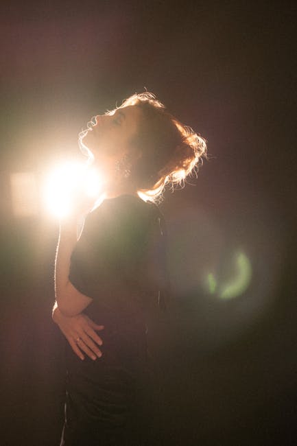 Elegant woman in dramatic backlit silhouette with glowing light effect.