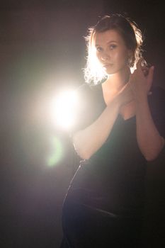 A stunning portrait of a woman in elegant pose, illuminated by dramatic backlighting.