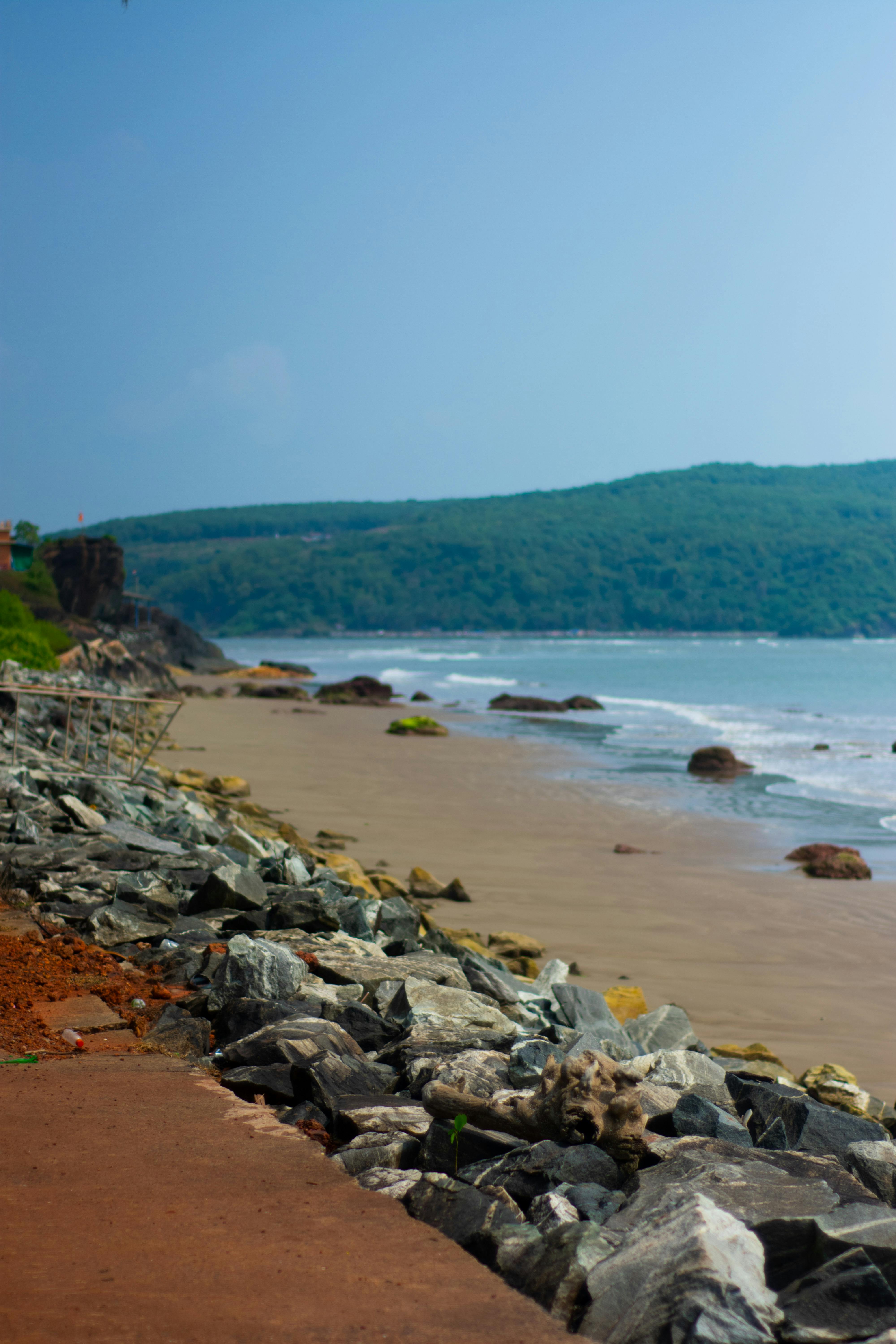 Explore the stunning coastal beauty of Gokarna's serene beach with rocky shores and lush hills.
