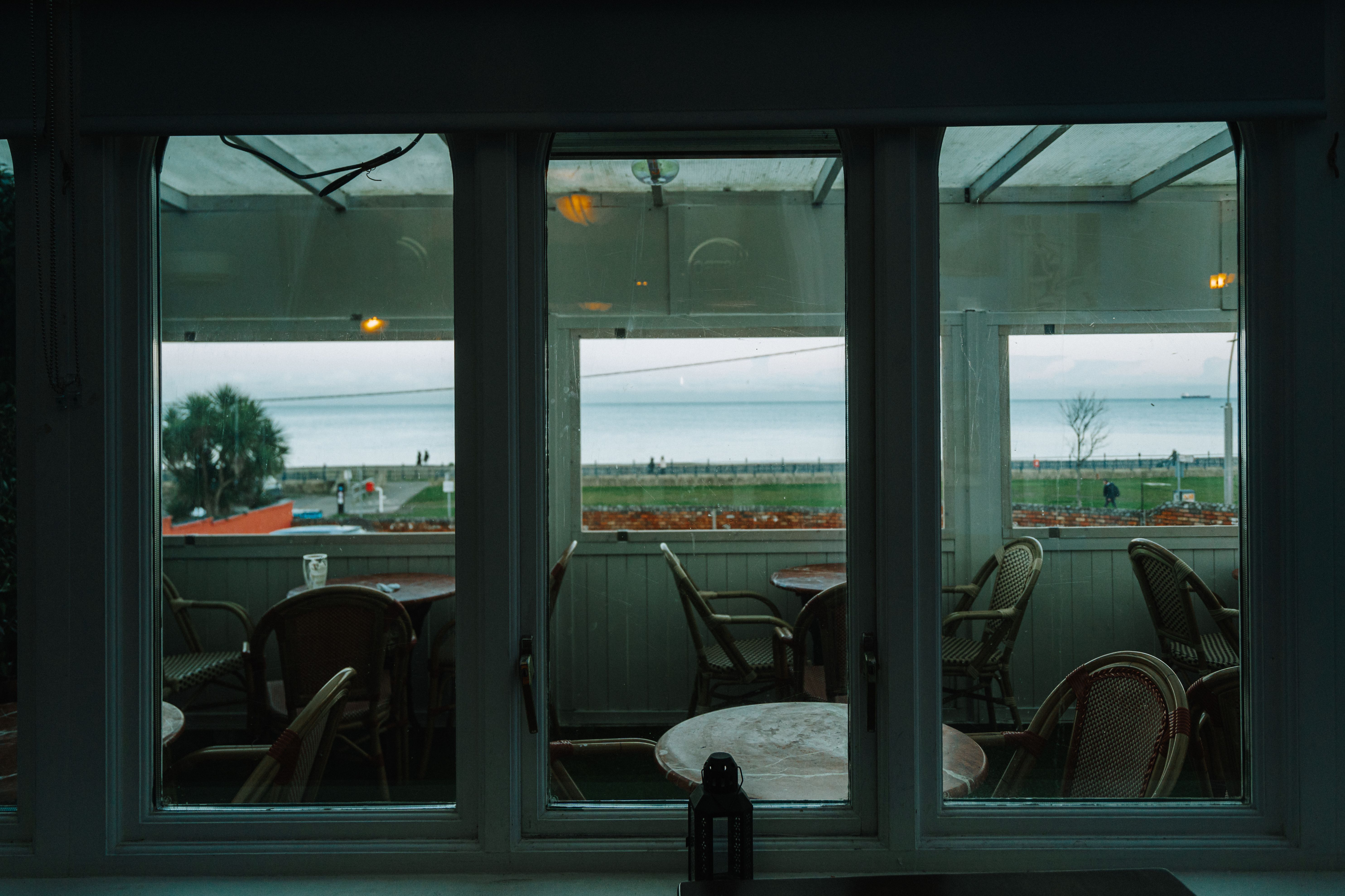Serene seaside view through empty cafe window, evoking tranquility.