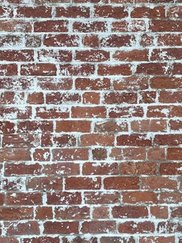 Close-up of an aged red brick wall with peeling white paint, perfect for backgrounds.