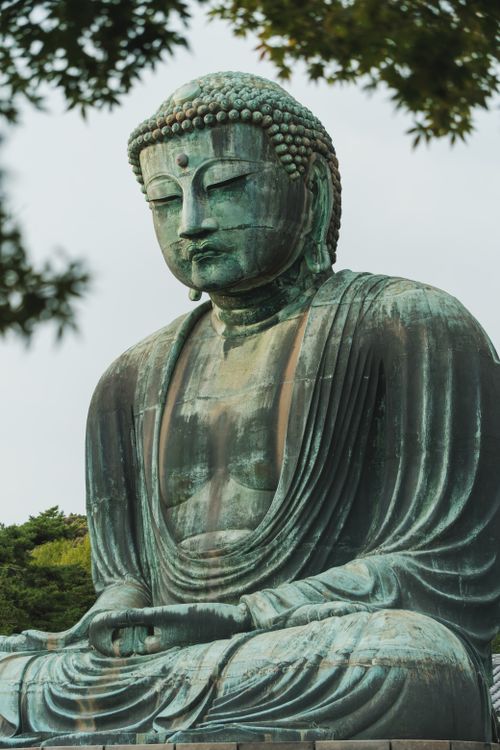 Free Kamakura's Great Buddha statue, surrounded by foliage and sky. Stock Photo