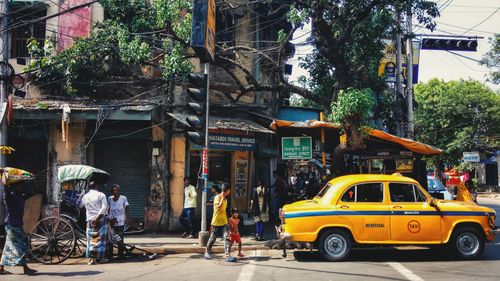 Free A vibrant street scene in Kolkata showing a classic yellow taxi and local life. Stock Photo