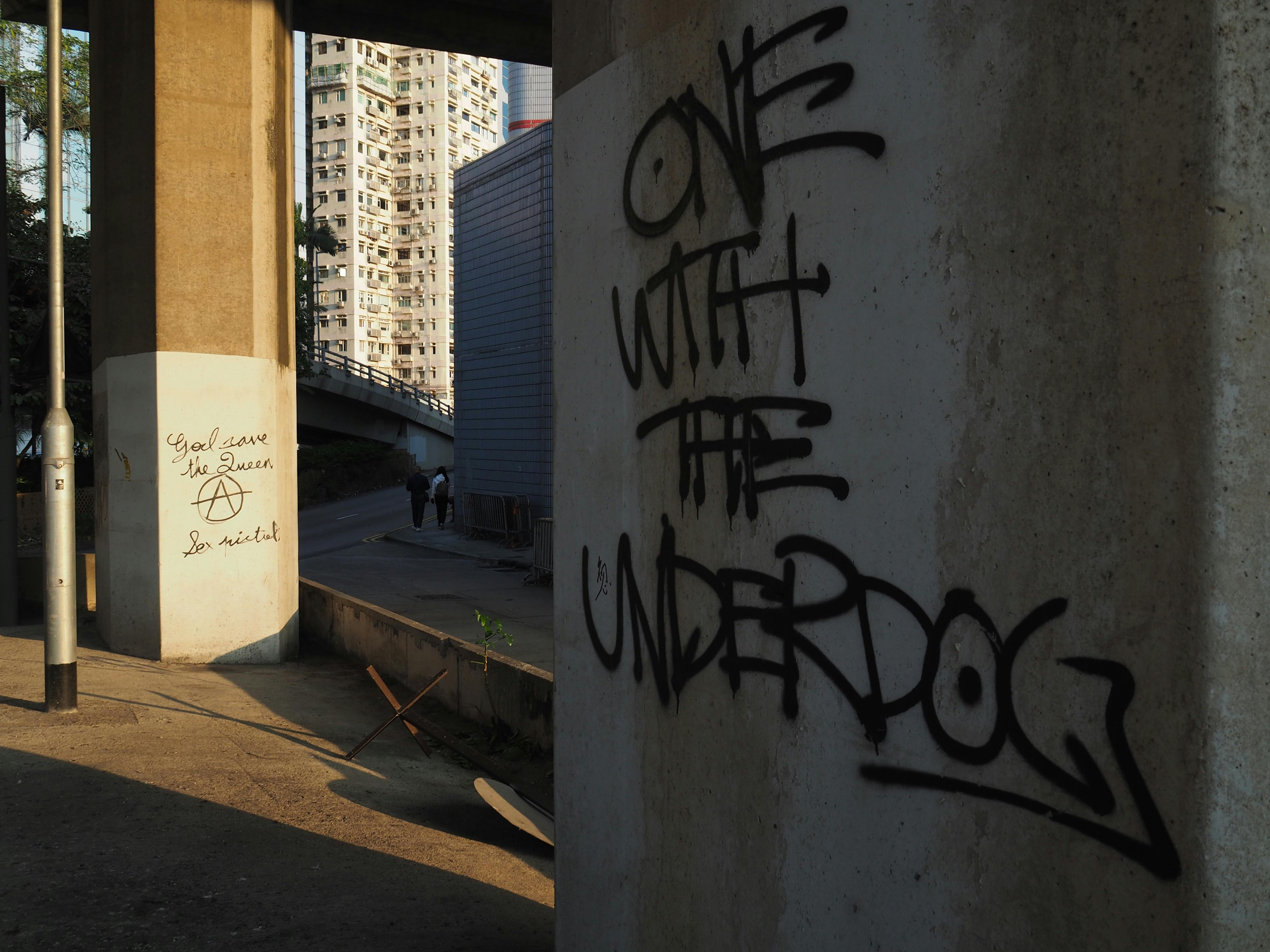 Graffiti art in an urban Hong Kong setting with high-rise buildings in the background.