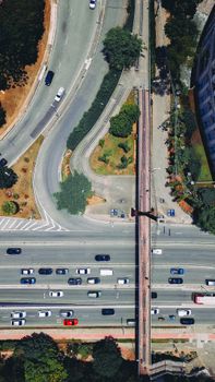 High-angle aerial shot of a busy urban road with vehicles and a pedestrian walkway.