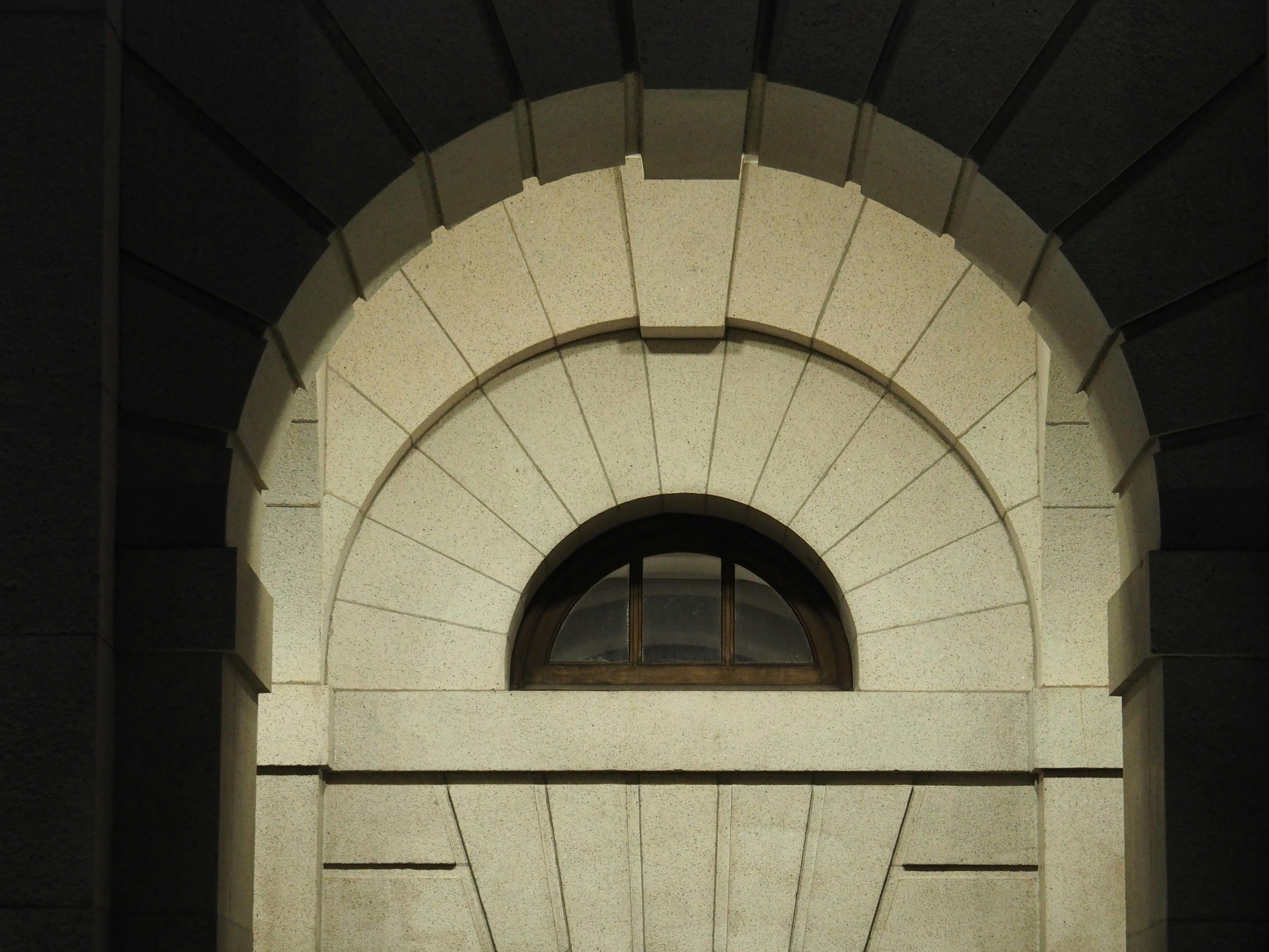 Sunlit stone arch window of a historical building facade in Hong Kong, showcasing classic architecture.