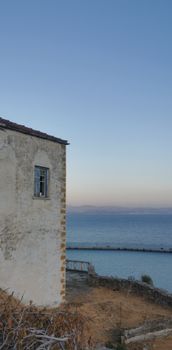 A rustic seaside house overlooking a calm ocean at twilight, capturing serene coastal beauty. — photo by Liv K.