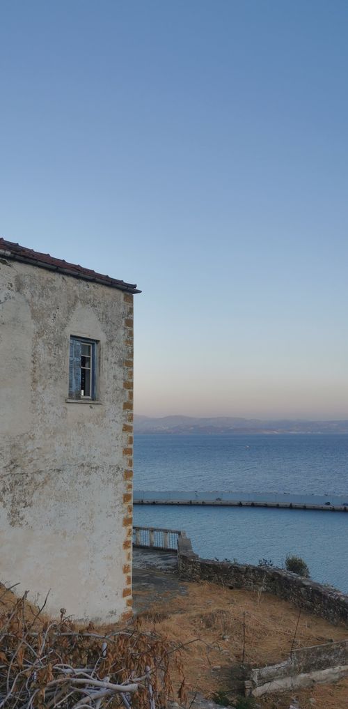 Free A rustic seaside house overlooking a calm ocean at twilight, capturing serene coastal beauty. Stock Photo