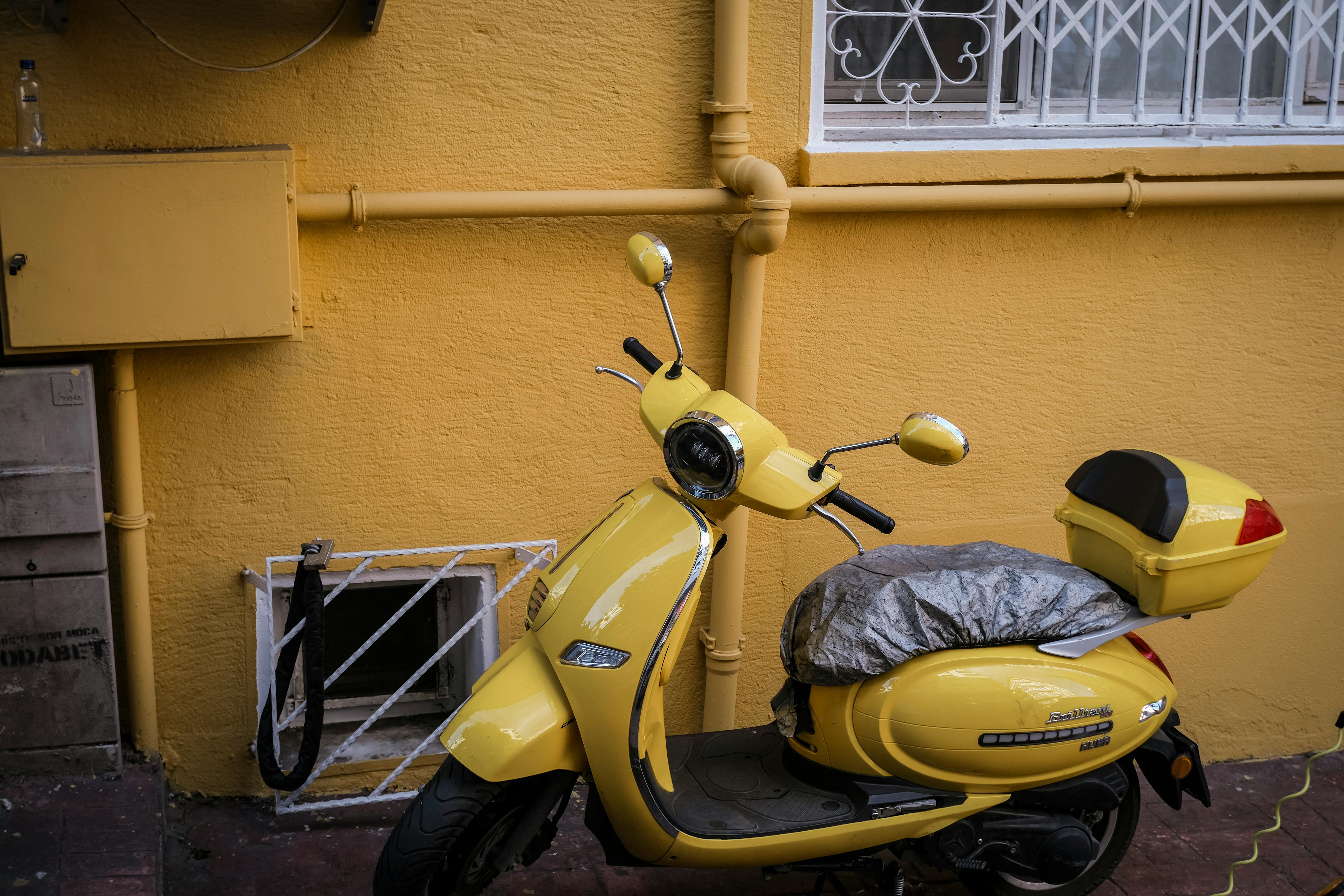 Free A yellow scooter parked against a matching painted wall in Istanbul, Türkiye. Stock Photo
