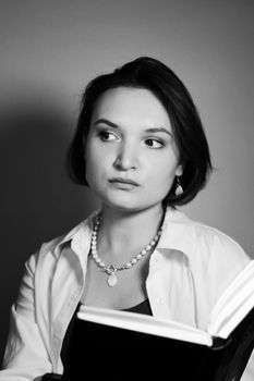 Black and white portrait of a woman reading, deep in thought.