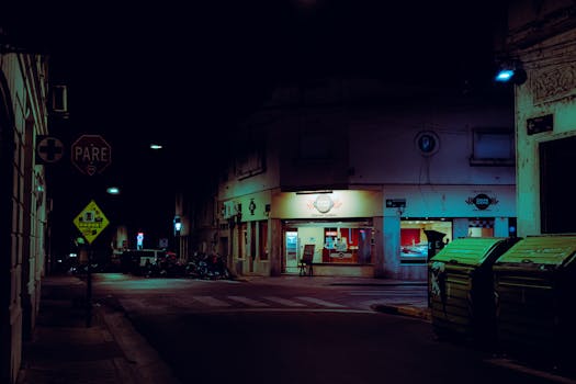Moody night scene of a street in Rosario, Argentina with neon lights.