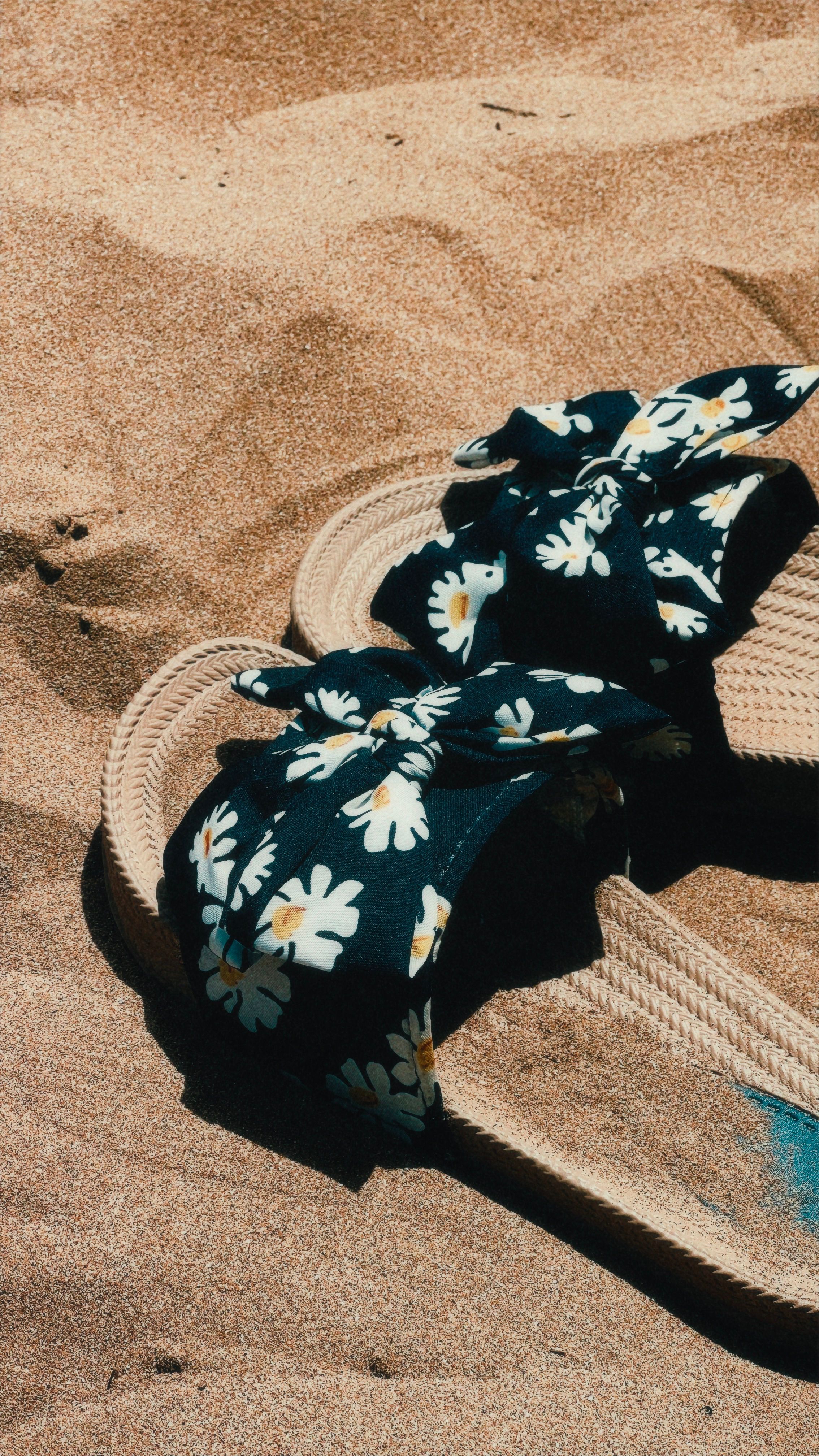 Stylish floral sandals rest on warm sandy beach in Agadir, Morocco.