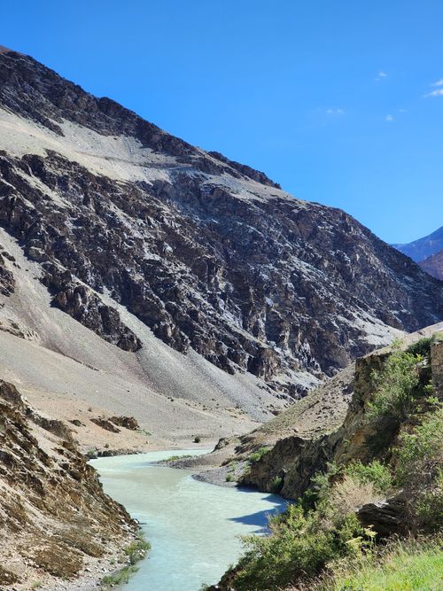 Free A stunning mountain valley with a river flowing under a clear blue sky. Perfect nature scene. Stock Photo