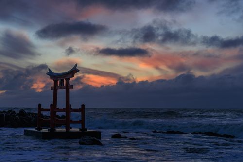 Free Torii gate silhouette against a stunning sunset sky over the waves in Shosambetsu, Hokkaido. Stock Photo