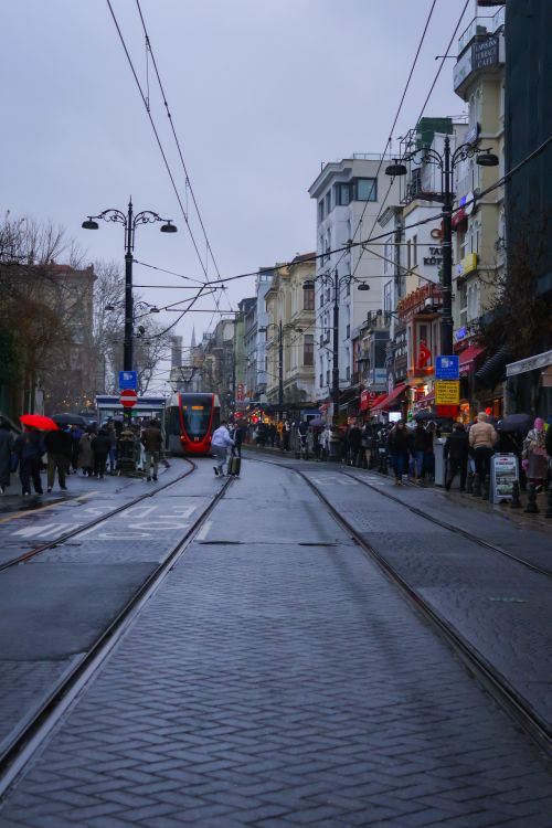 Free A bustling street in Istanbul with a modern tram and people, captured on a rainy day. Stock Photo