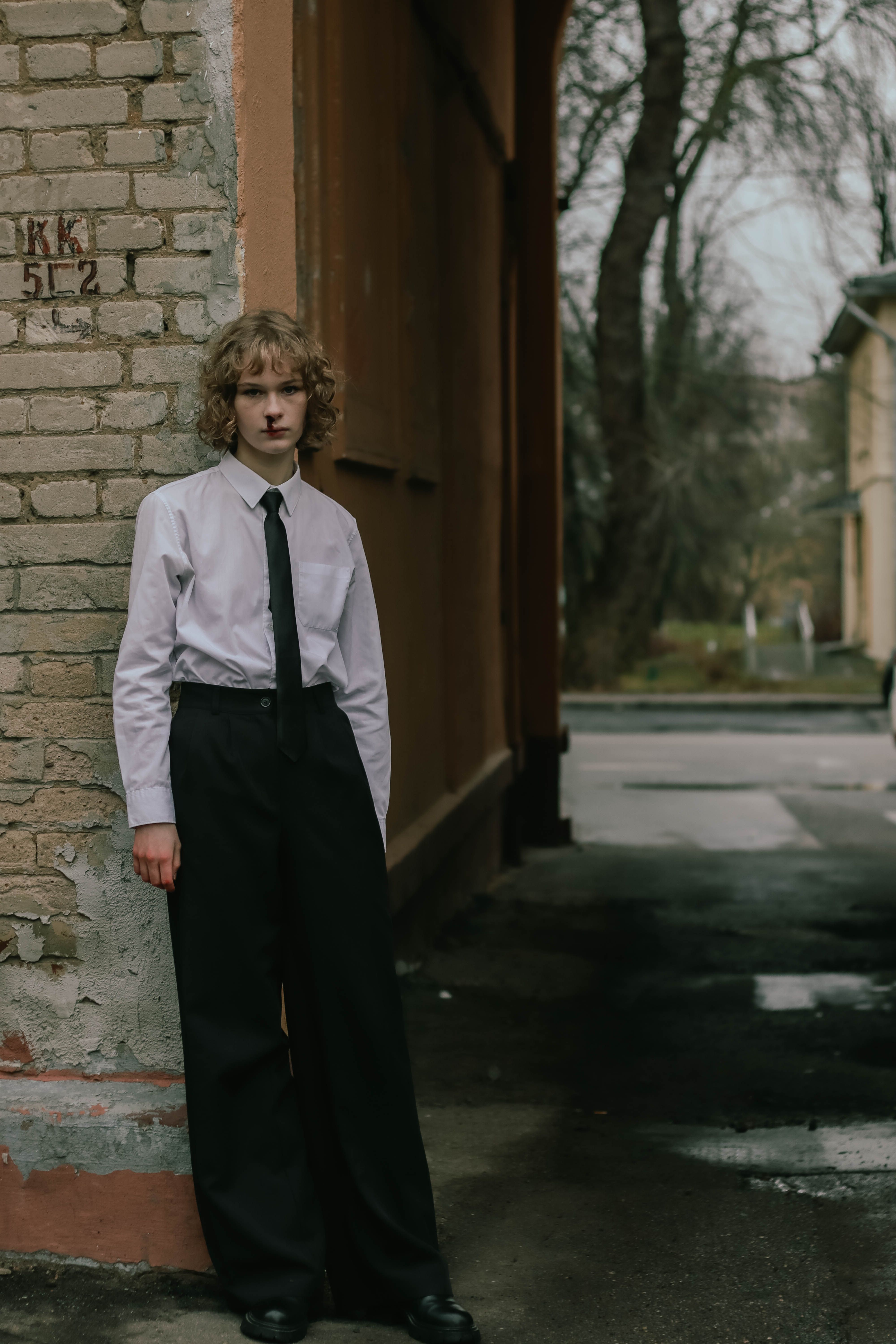 Young person in formal attire standing outdoors near brick wall in Minsk, Belarus.
