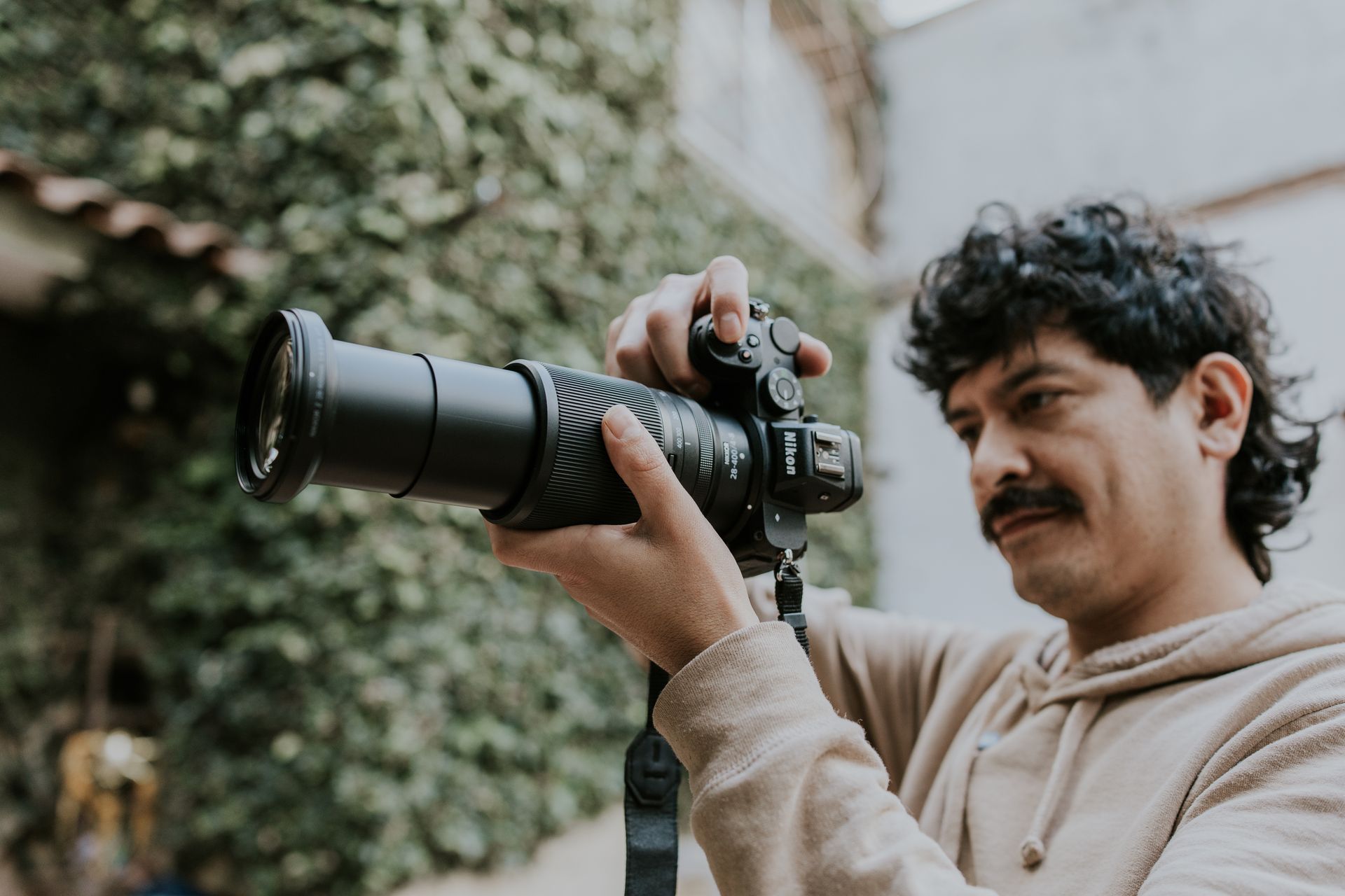 A photographer adjusts settings on a Nikon camera with a telephoto lens outdoors.