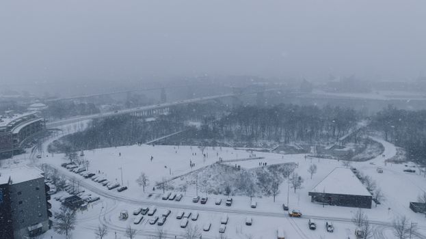 Aerial view of snow-covered city park and skyline in winter.
