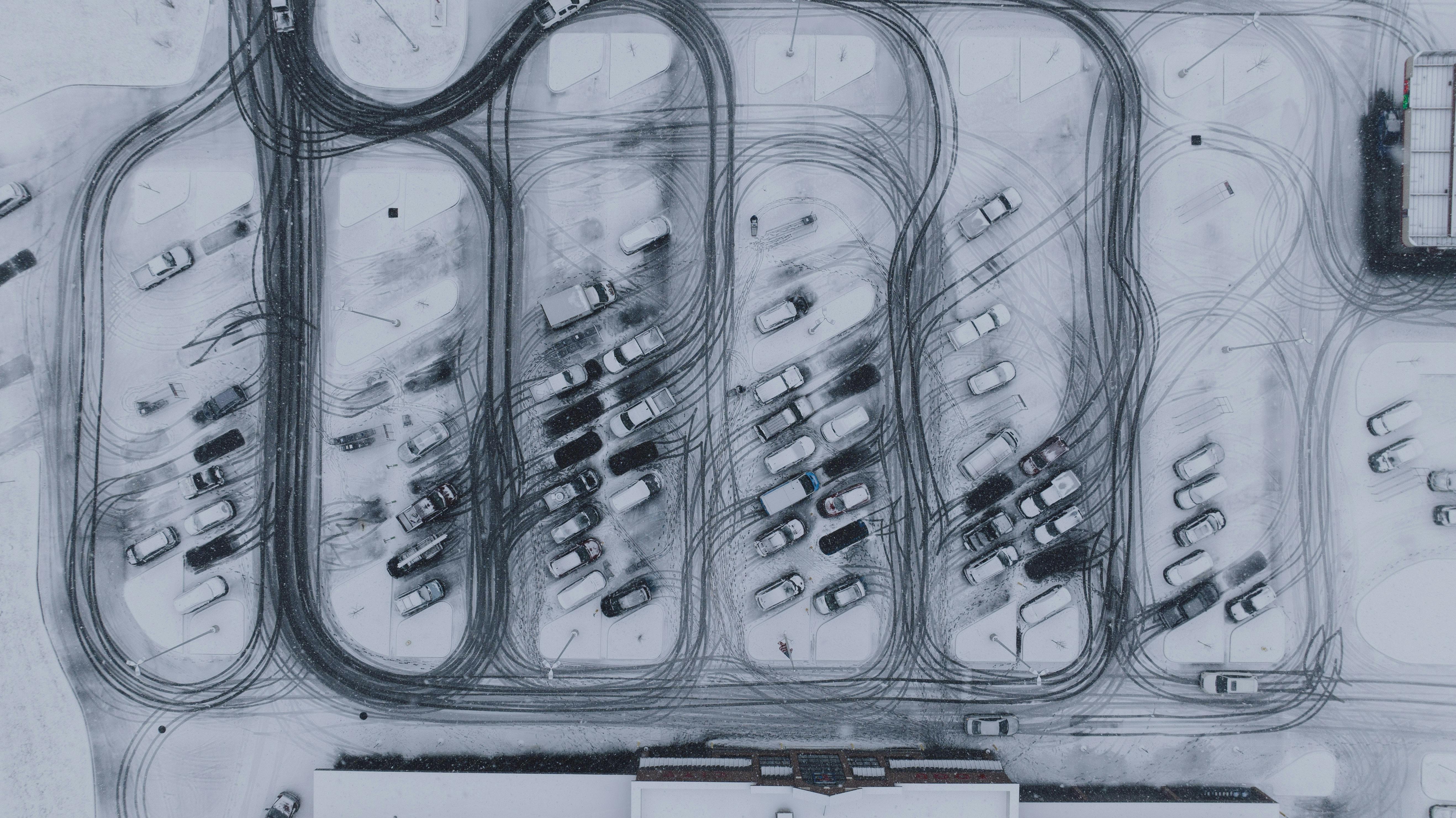 bezplatná Pohled z dronu na zasněžené parkoviště plné aut a složitých stop pneumatik. Základová fotografie