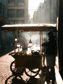 Backlit street vendor interaction in Istanbul's early morning sun.
