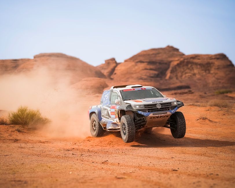 Exciting rally car speeding through a desert landscape, kicking up dust in a thrilling race.