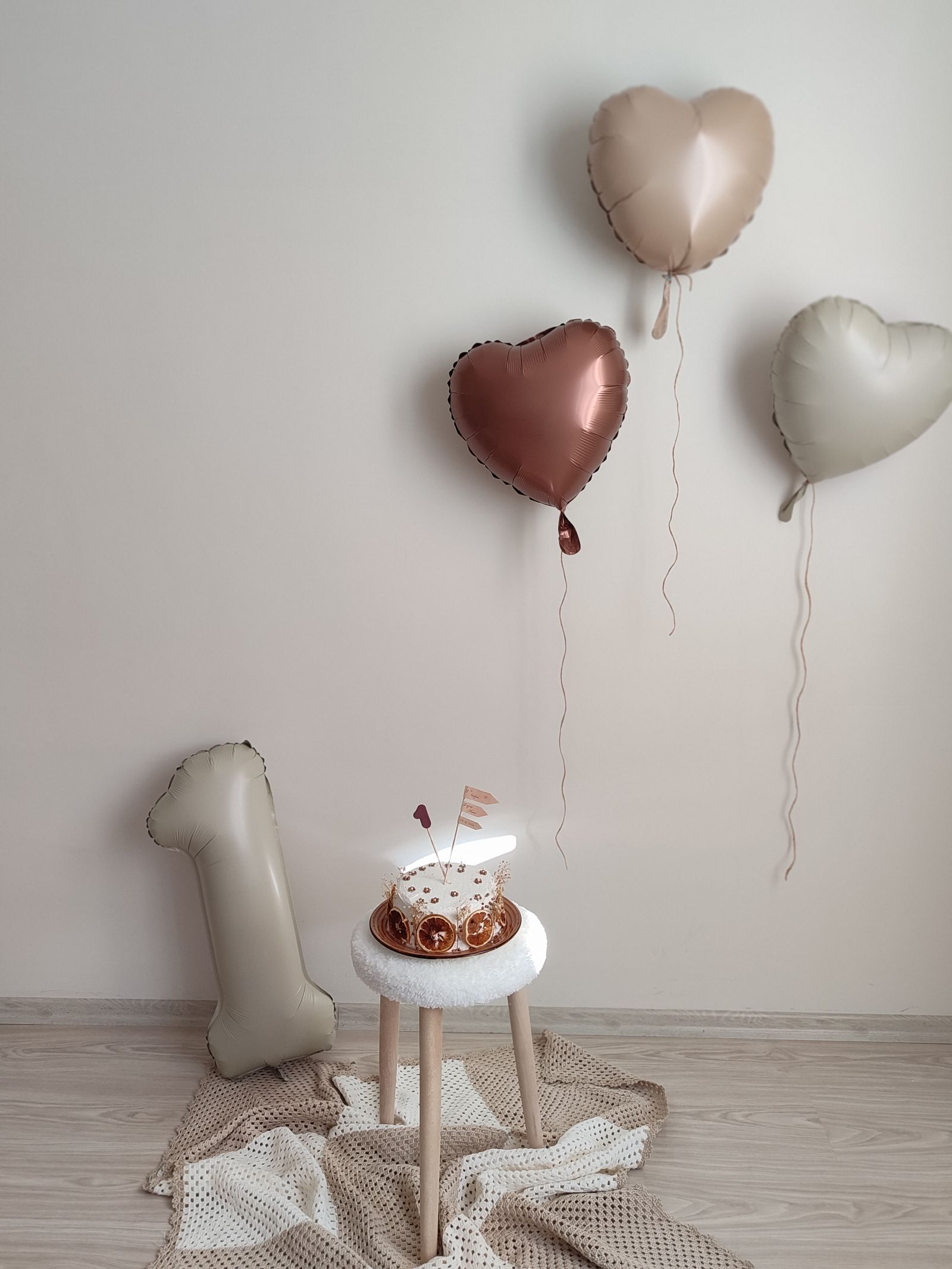 Minimalist first birthday setup with cake and number one balloon