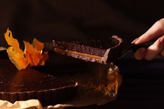 Close-up of a rich chocolate tart slice with caramel, perfect for desserts or food blogs.