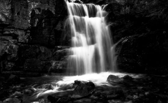 A serene black and white long exposure photograph capturing a cascading waterfall.