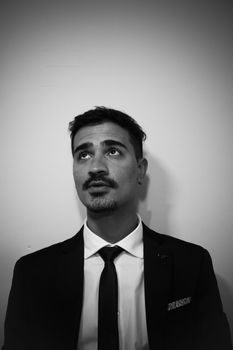 Black and white portrait of a young man in a suit looking upwards.