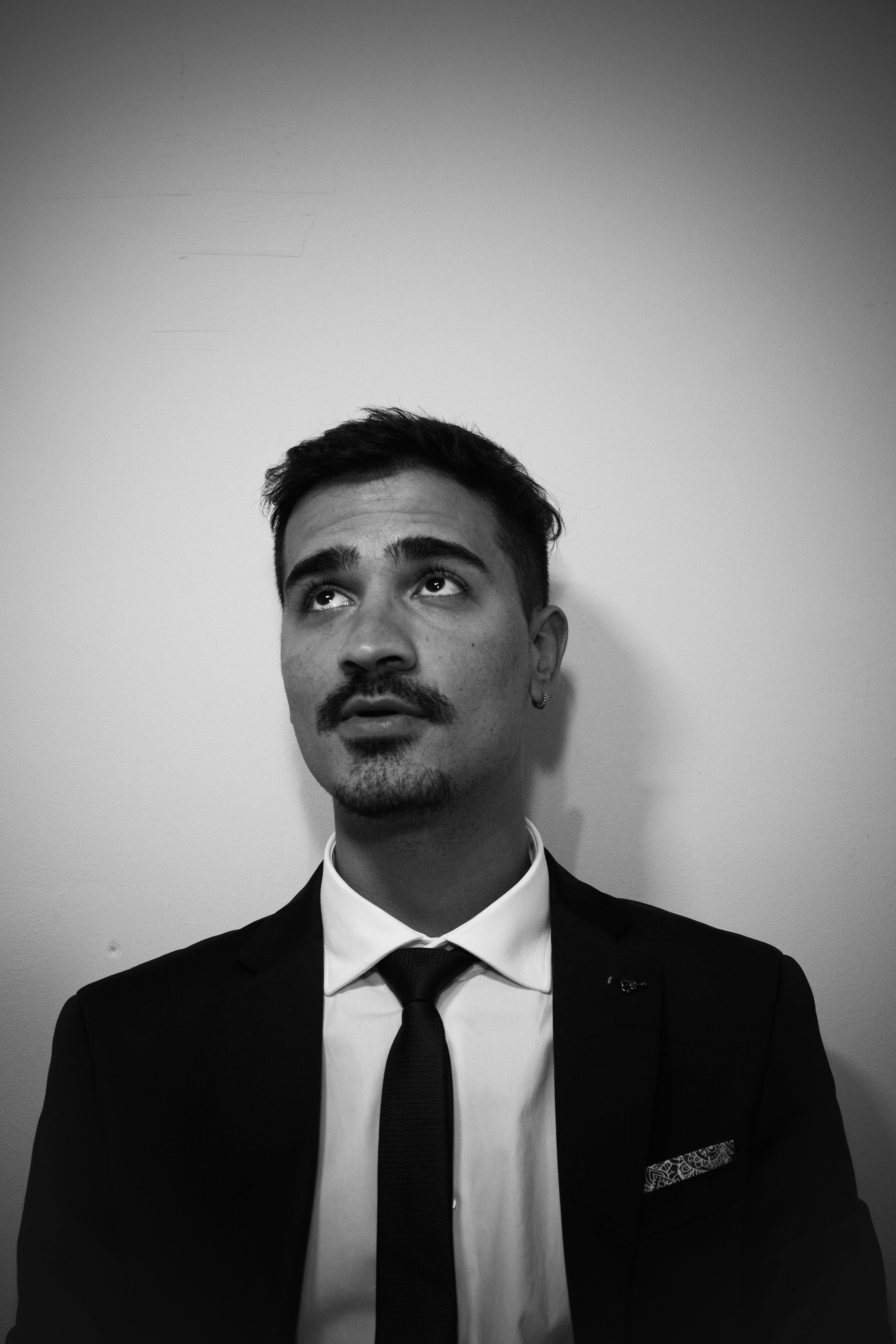 Gratis Ritratto in bianco e nero di un giovane uomo in giacca e cravatta che guarda verso l'alto. Foto a disposizione