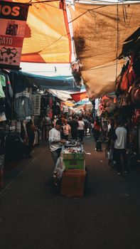 A vibrant scene of a crowded street market with vendors and colorful canopies.
