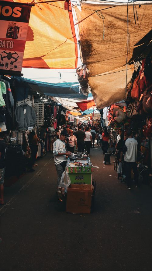 Free A vibrant scene of a crowded street market with vendors and colorful canopies. Stock Photo