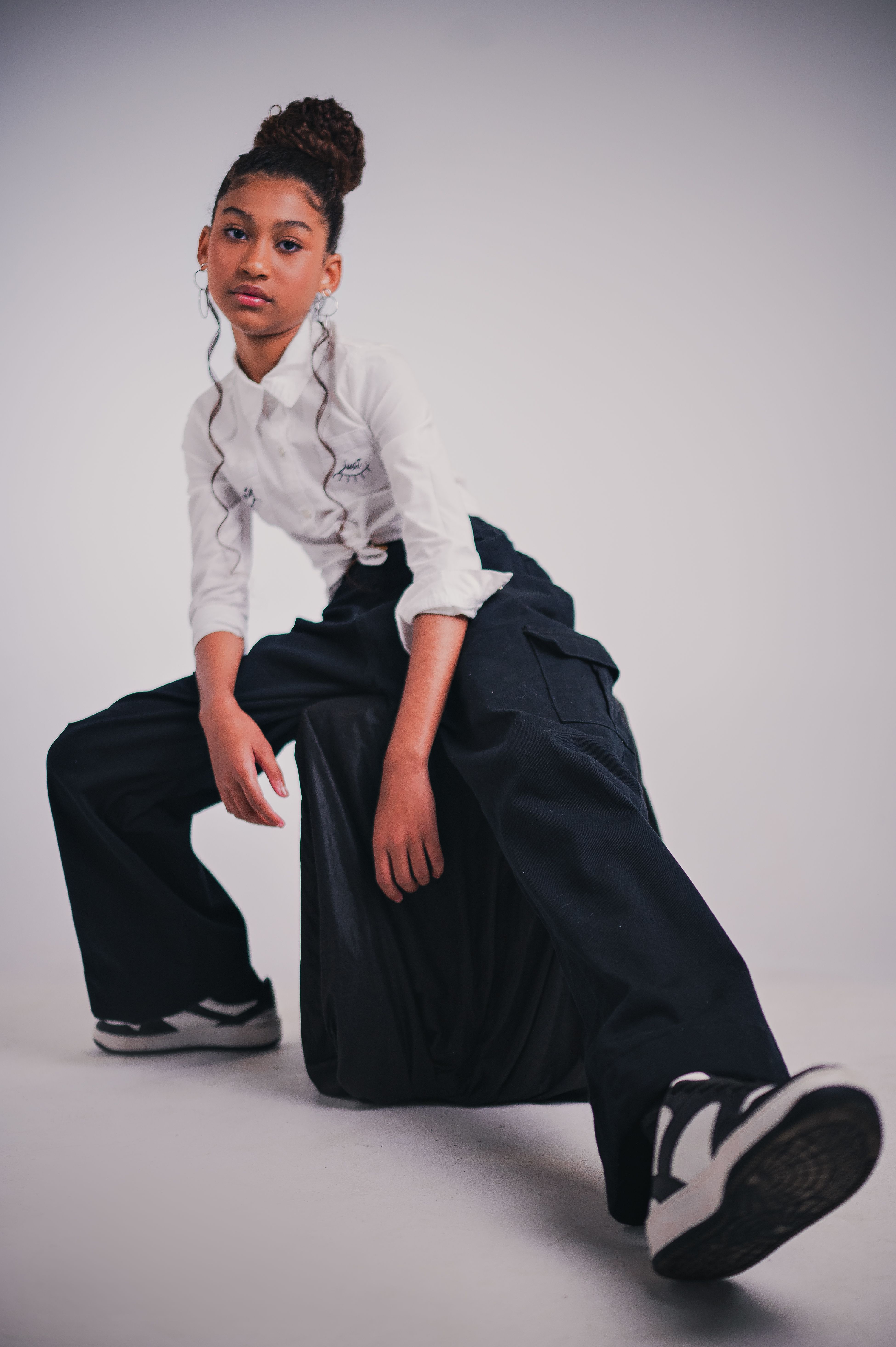 Teen girl in chic fashion posing confidently in studio lighting.