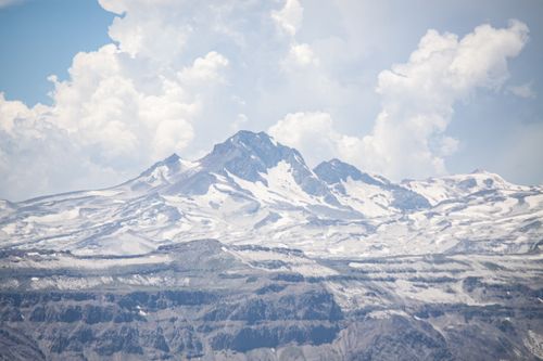 Free Capture the serene beauty of the snow-covered Andes Mountains in Maule, Chile under a vast, cloud-streaked sky. Stock Photo