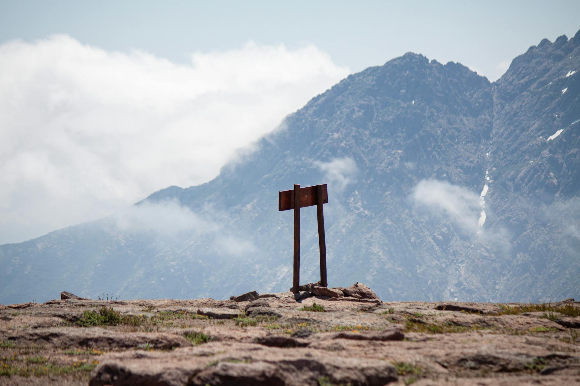 A solitary rustic signpost stands against the majestic backdrop of the Maule mountain range in Chile.