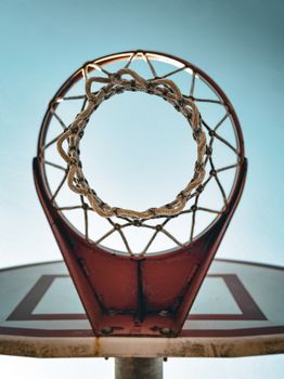 Looking up through a basketball hoop with a clear sky background.