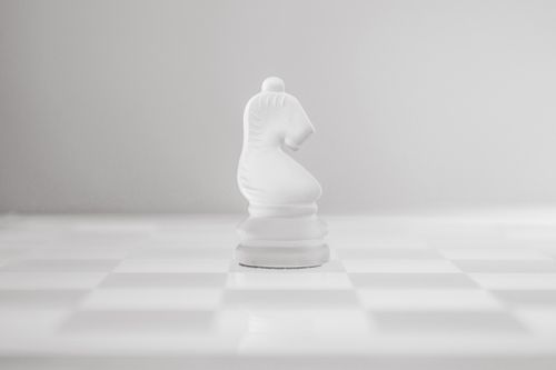 Free Close-up of a white chess knight on a chessboard with a minimalist design. Stock Photo