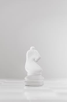 A white chess knight piece elegantly displayed on a minimalist board, symbolizing strategy and intelligence.
