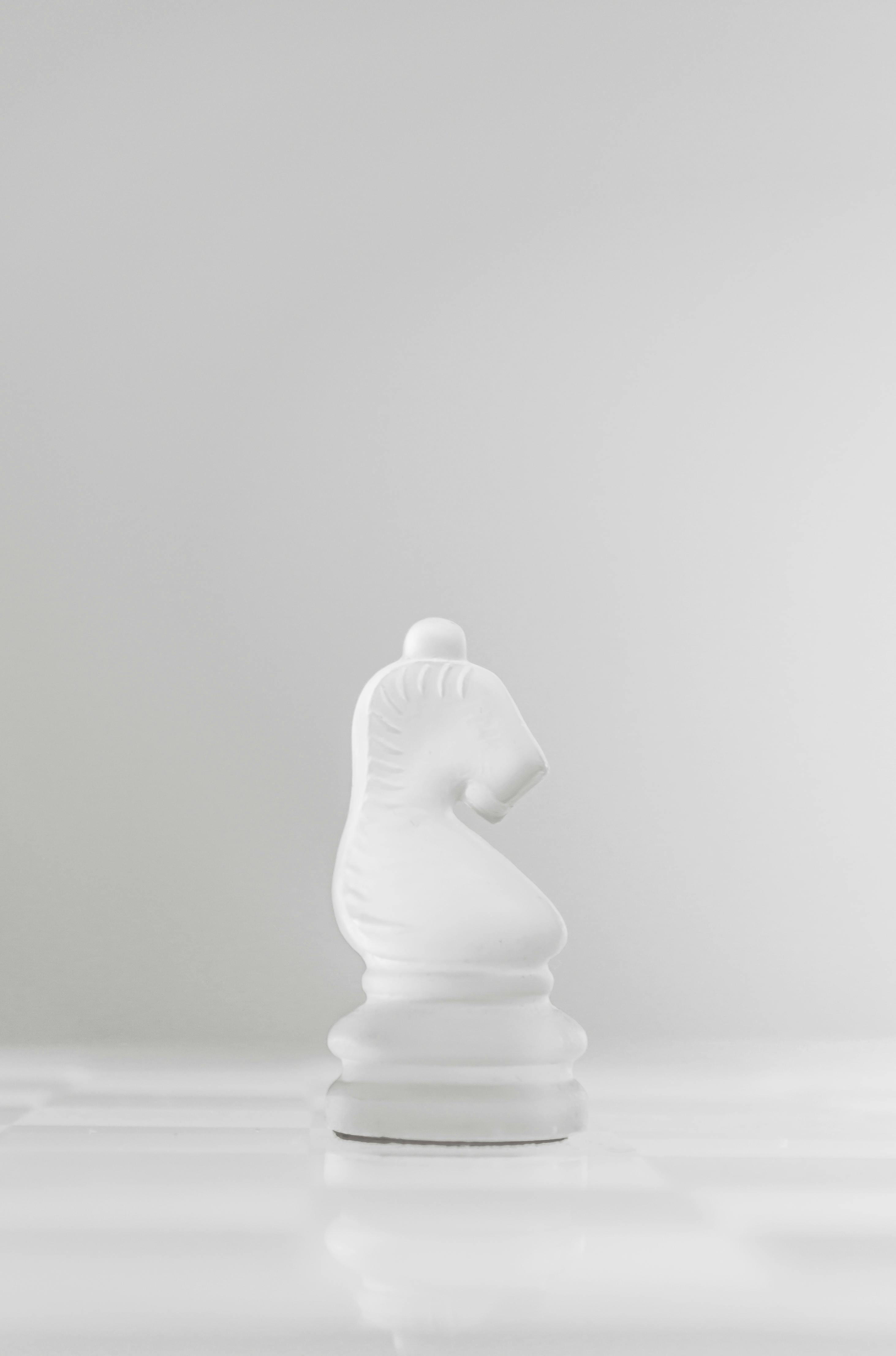 Gratis En hvit sjakkridderbrikke elegant vist på et minimalistisk brett, som symboliserer strategi og intelligens. Arkivbilde