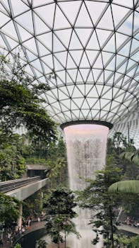 Indoor waterfall at Jewel Changi Airport, Singapore, surrounded by lush greenery.