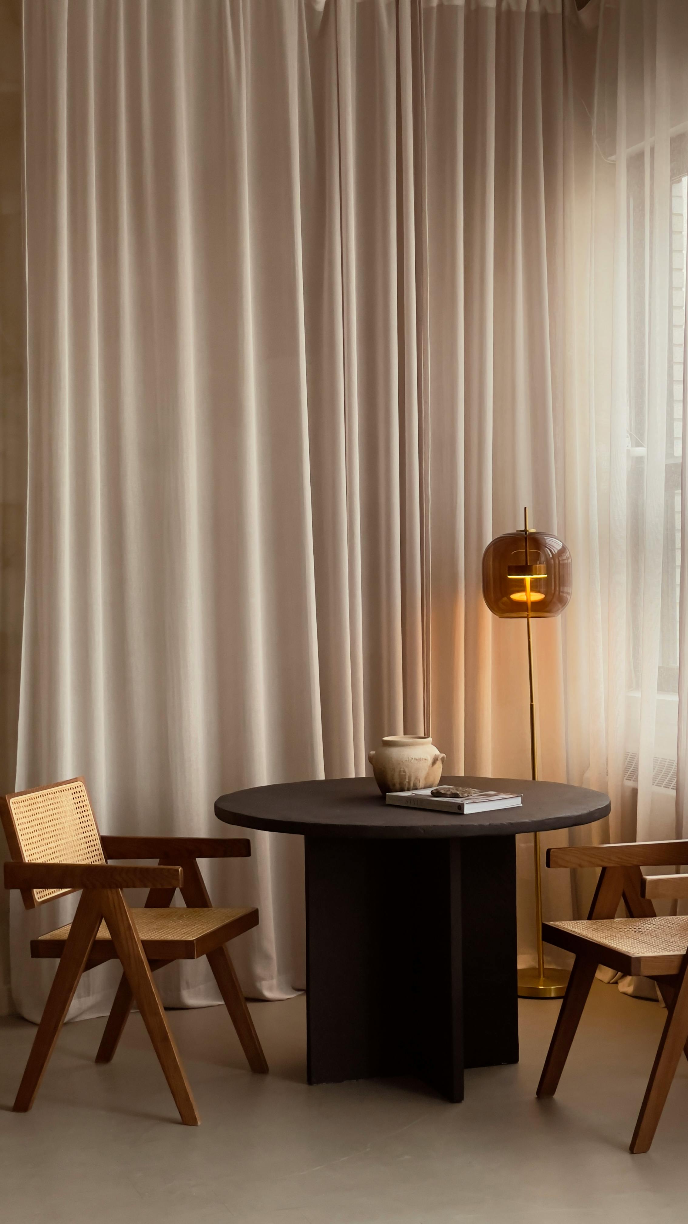 Cozy minimalist interior featuring a black table, wooden chairs, and warm lighting.
