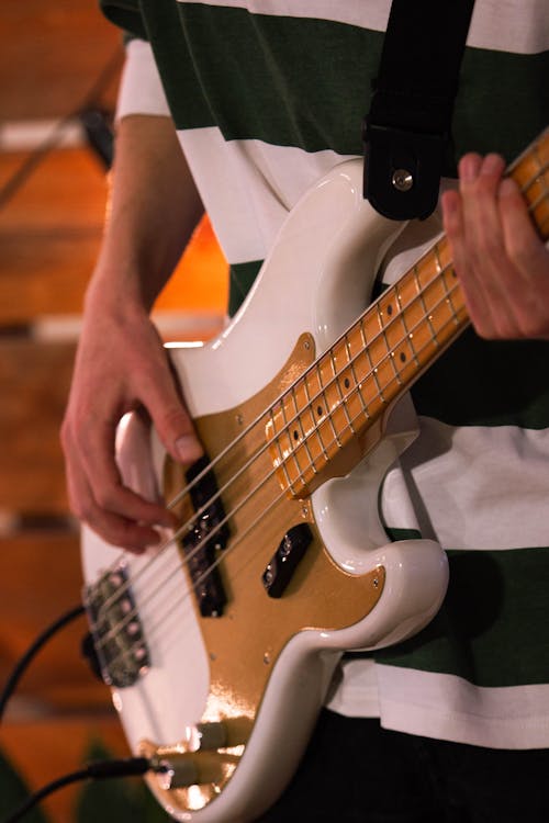 Free A musician skillfully playing a white electric bass guitar in a studio setting. Stock Photo
