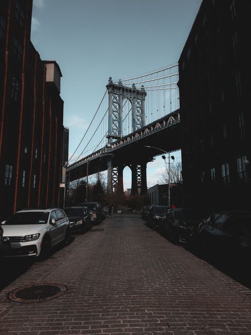 Free View of the Manhattan Bridge between city buildings, capturing an urban street scene. Stock Photo