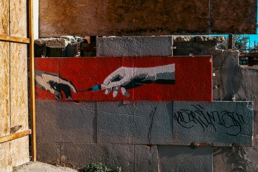 Vibrant street art on a demolished wall in Istanbul, Türkiye, depicting hands exchanging a syringe.