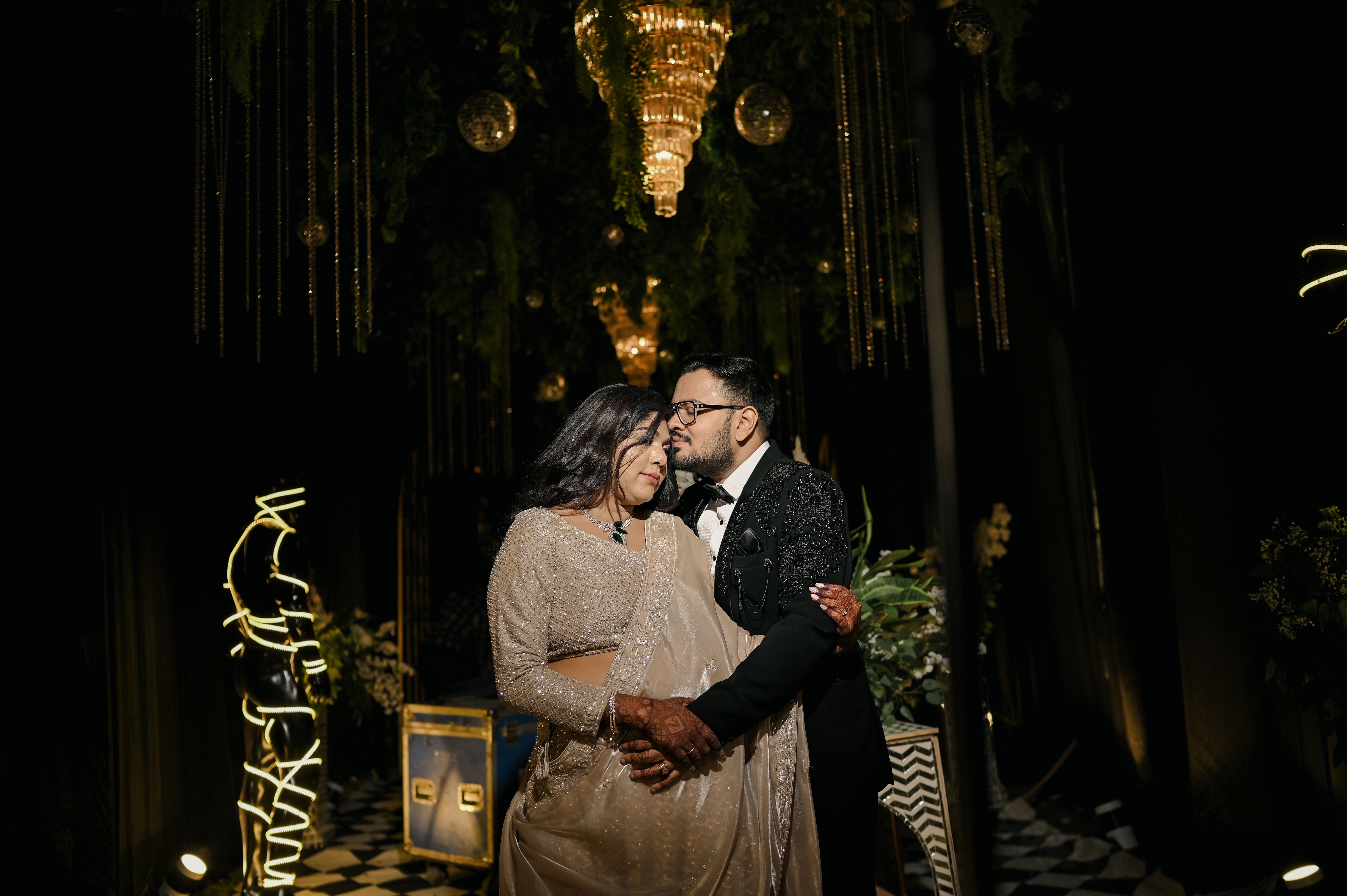 Elegant couple embracing at an evening gala event under chandeliers.